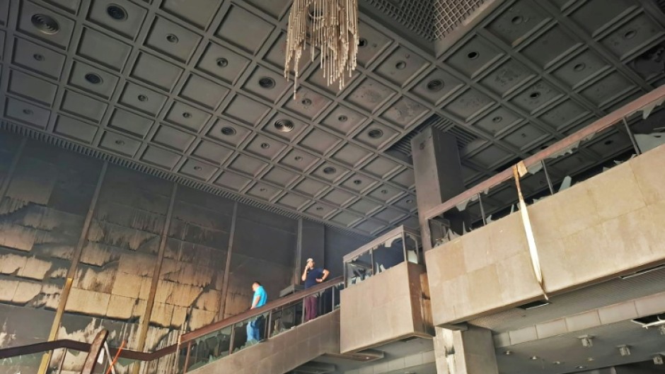 Locals look at the charred remains of the ravaged Parliament building in Kathmandu