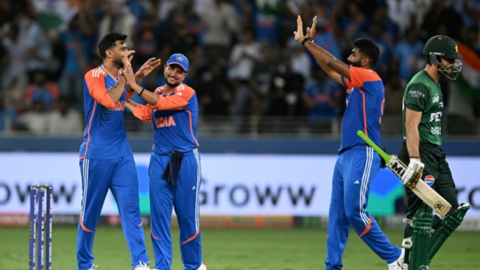 Pakistan captain Salman Agha (R) walks back to the pavilion after his dismissal by Axar Patel (L)