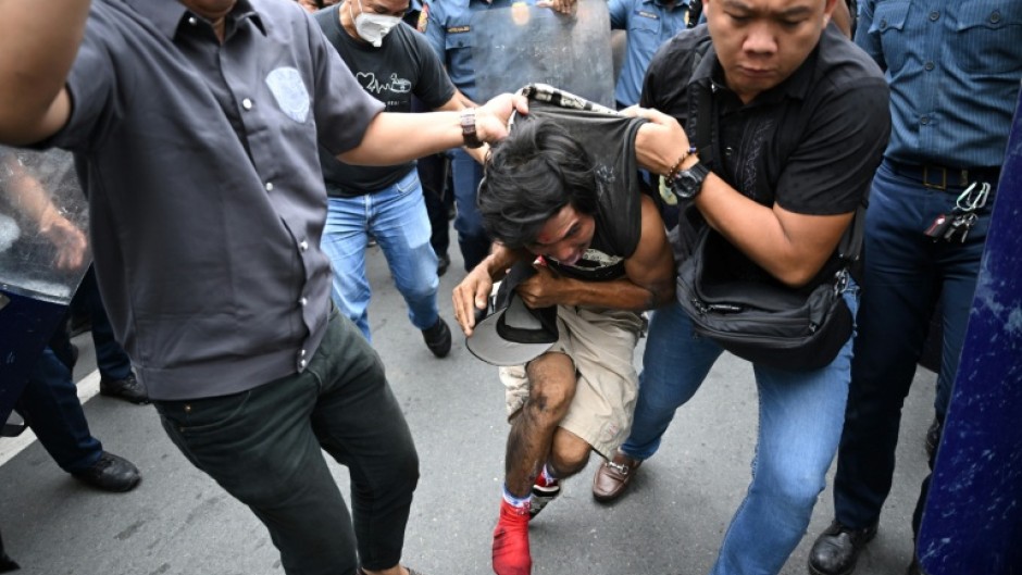 A protester suspected of clashing with police is arrested near the presidential palace in Manila on Sunday