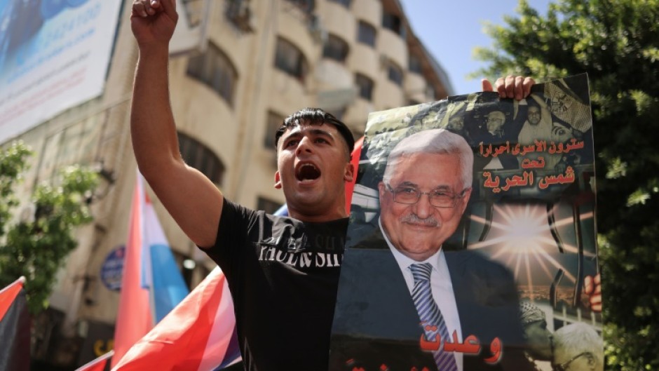 A Palestinian chants slogans in Ramallah while holding a portrait of Palestinian Authority President Mahmud Abbas
