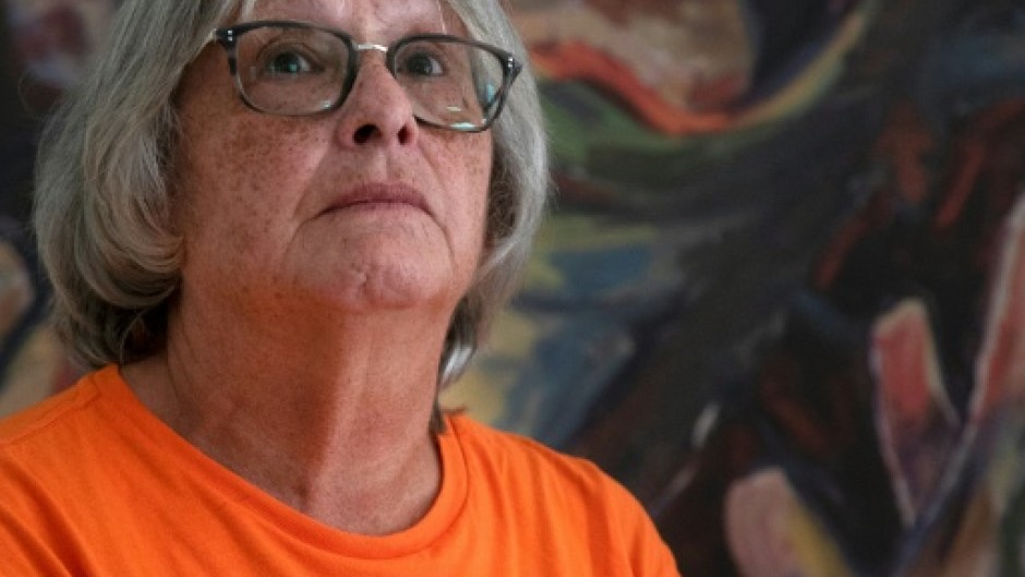 Roberta Hill, residential school survivor from the Mohwak Institute, poses next to a painting by Robert Gary Miller, also a survivor of the Mohawk Institute, during the site's unveiling as a museum in Brantford, Ontario on September 30, 2025