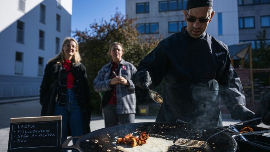 Onlookers watch as workers prepare a dish that can be made under emergency conditions