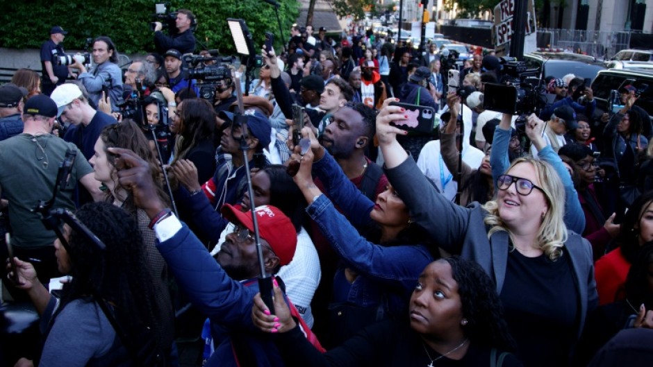 People wait outside Manhattan Federal Court to catch a glimpse of Sean "Diddy" Combs' family following his sentencing on two counts related to prostitution