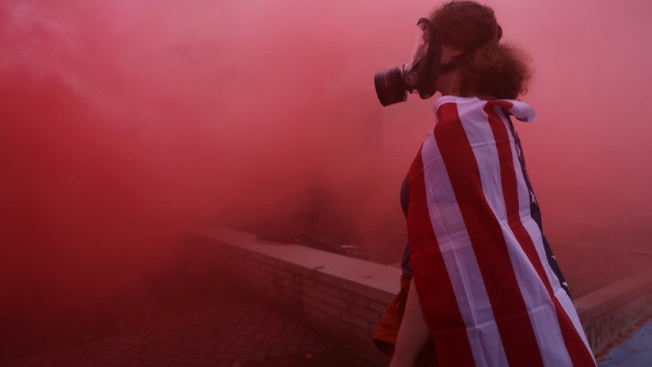A protester stands in the haze from a smoke grenade outside of a downtown Portland U.S. Immigration and Customs Enforcement (ICE) facility