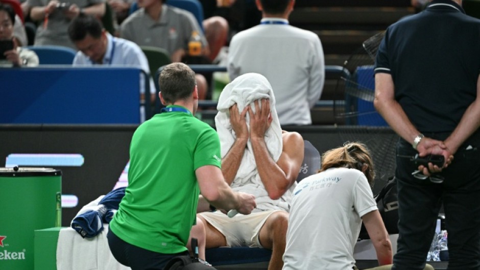 Novak Djokovic wipes his face as he receives medical attention