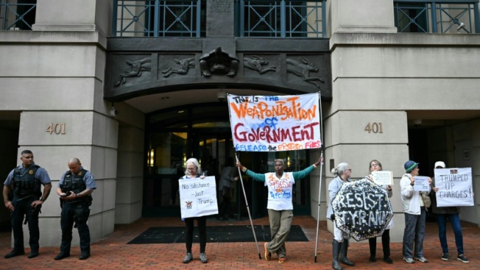 Demonstrators protest outside of the Albert V. Bryan United States Courthouse ahead of the arraignment of former FBI director James Comey