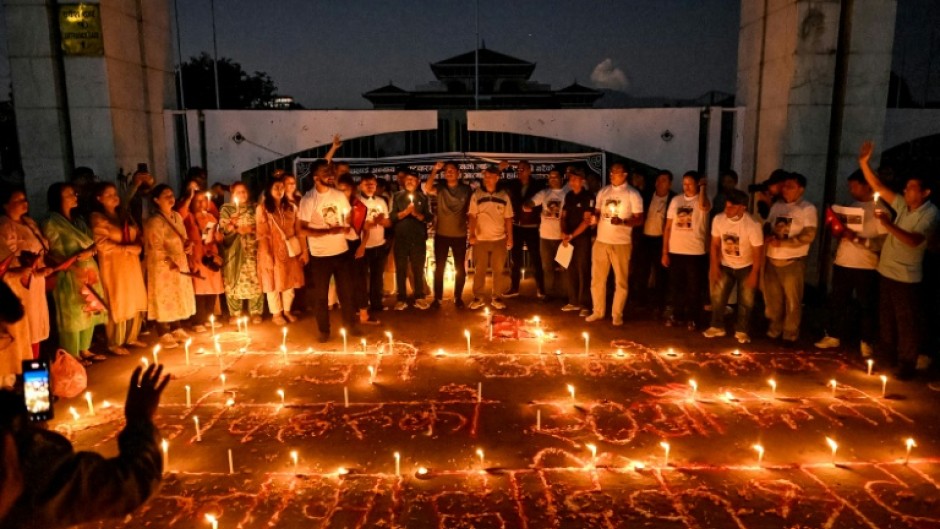 Nepalis lit candles outside the fire-damaged parliament building on Thursday, one month after anti-corruption protests toppled the government and left dozens dead