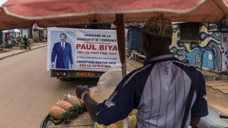 A street vendor sells pineapple slices next to a campaign truck Cameroon President Paul Biya