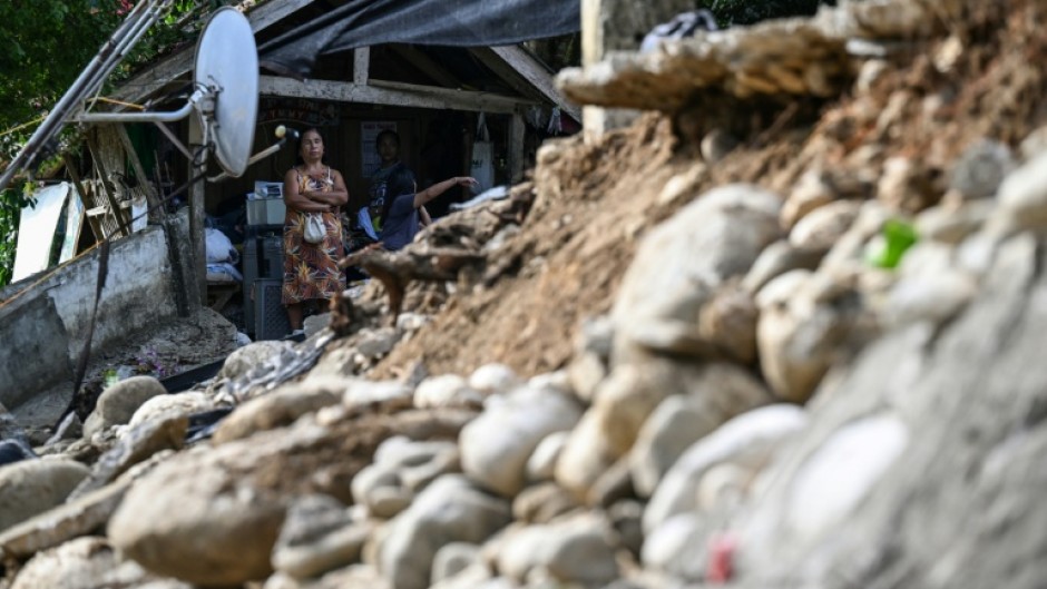 A woman looks at a damaged house in Manay on October 11, 2025, after two powerful quakes struck off the southern Philippines on October 10