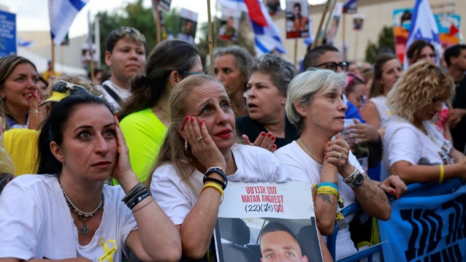 Des Israéliens brandissant des portraits d’otages israéliens encore retenus à Gaza attendent leur libération sur la place des Otages à Tel-Aviv, tôt le 13 octobre 2025