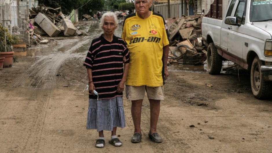 Hilario Reynosa and his wife Elodia Reyes, who survived the flooding in the Morelos neighborhood after being trapped by the overflowing Cazones River, pose for a portrait on a street covered by debris in Poza Rica, Mexico