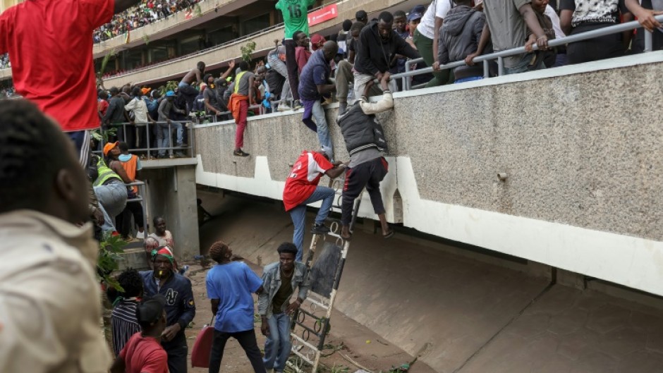 Kenyans run for cover as security forces fire in a stadium where they gathered to view the coffin of Raila Odinga