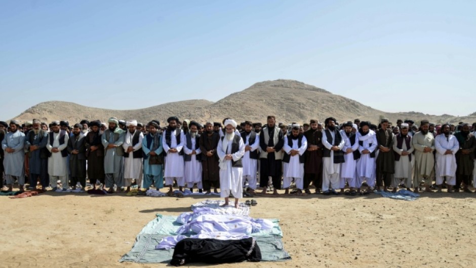 Relatives offer prayers during a funeral ceremony in the Spin Boldak district of Kandahar province after the cross-border clashes