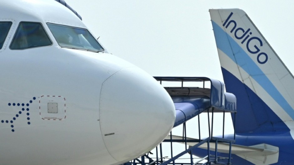 Ground staff walk past an IndiGo airlines aircraft taxiing in the apron at the Netaji Subhash Chandra Bose International Airport in Kolkata in February 2024