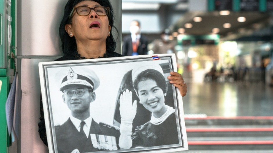 Thai mourner Kanjana Malaithong holds a portrait former queen Sirikit and king Bhumibol Adulyadej as she weeps at Chulalongkorn Hospital in Bangkok