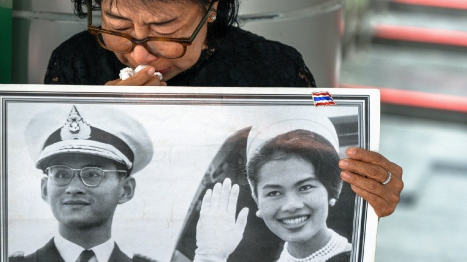 A mourner cries as she holdas a portrait of former Thai Queen Sirikit, who died in a Bangkok hospital at the age of 93