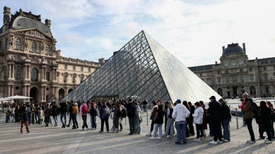 Visitors queue to get in to the Louvre, days after it was robbed in Paris