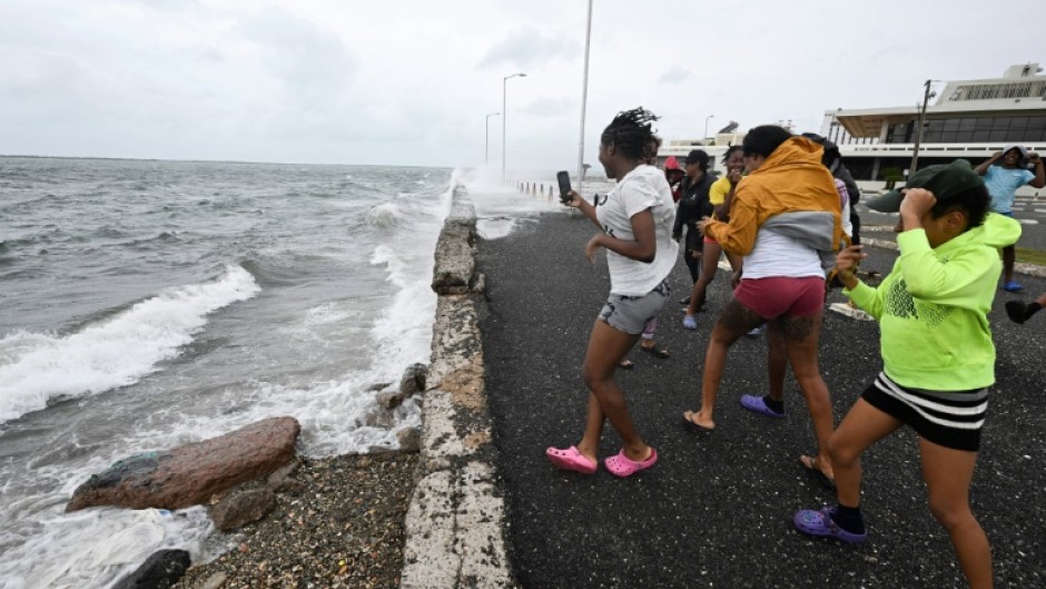 Teenagers gather at the Bank of Jamaica's parking lot on the waterfront in Kingston on October 27, 2025