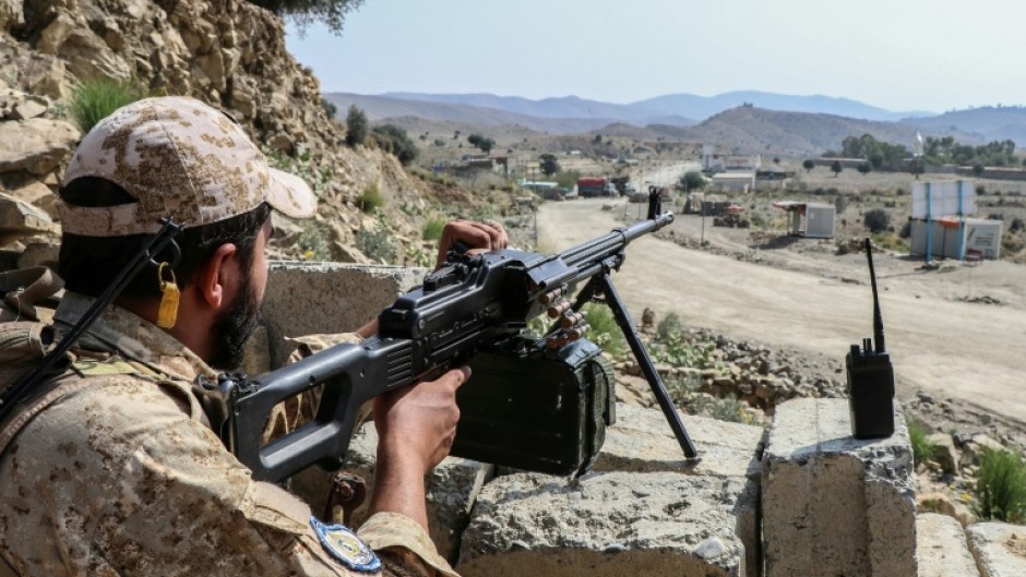 A Taliban security personnel stands guard along a road near the Ghulam Khan zero-point border crossing between Afghanistan and Pakistan