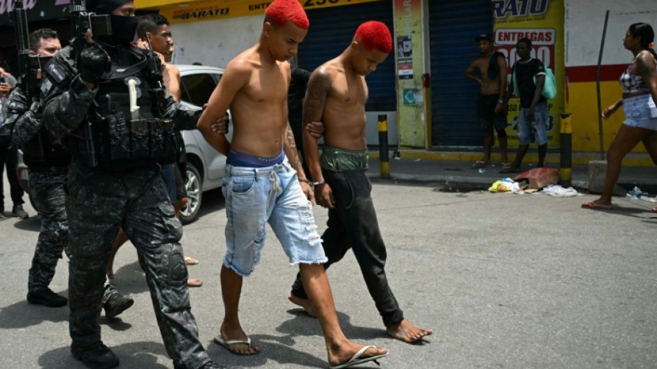 Police officers escort suspects arrested during the raid