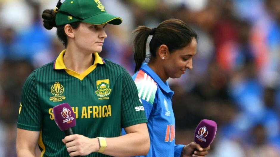 South Africa's captain Laura Wolvaardt (L) and India's skipper Harmanpreet Kaur prepare for interviews after the World Cup final coin toss