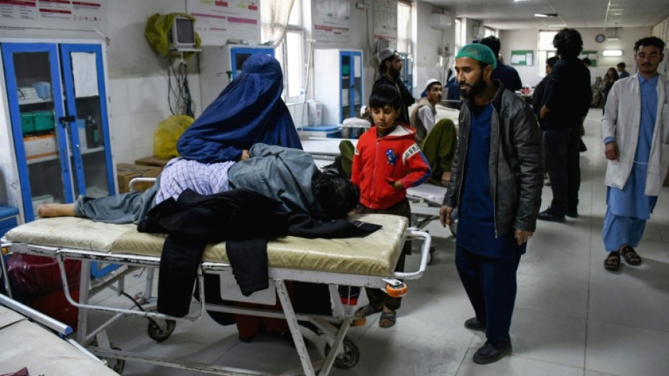 An Afghan woman sits beside an earthquake victim receiving treatment at a hospital in Mazar-i-Sharif on November 3, 2025, after a 6.3-magnitude quake struck overnight, killing at least 20 people -- just months after another deadly tremor shook the country