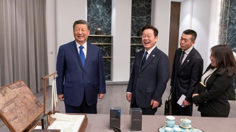 Chinese leader Xi Jingping (L) joked about spying as he gave South Korean President Lee Jae Myung a pair of Chinese smartphones