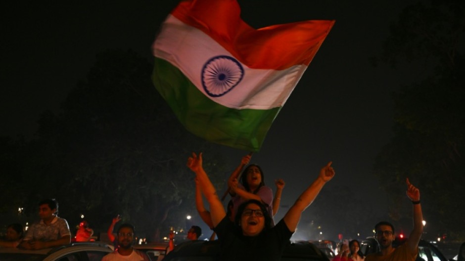 Fans wave flags as they celebrate India's victory in New Delhi