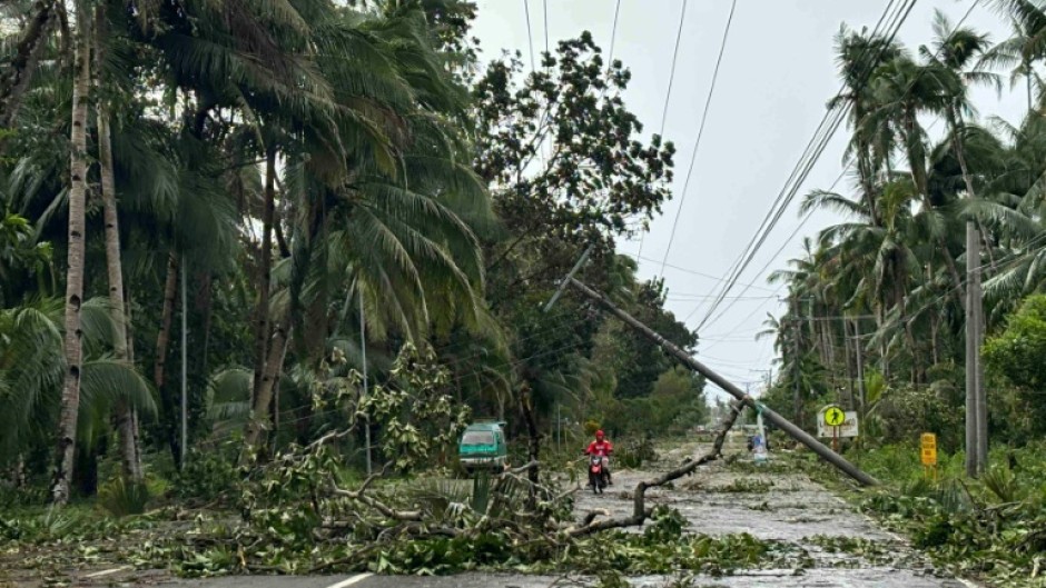 A motorist drives past a fallen electric post and trees on a highway in the aftermath of Typhoon Kalmaegi in Mayorga, Leyte province