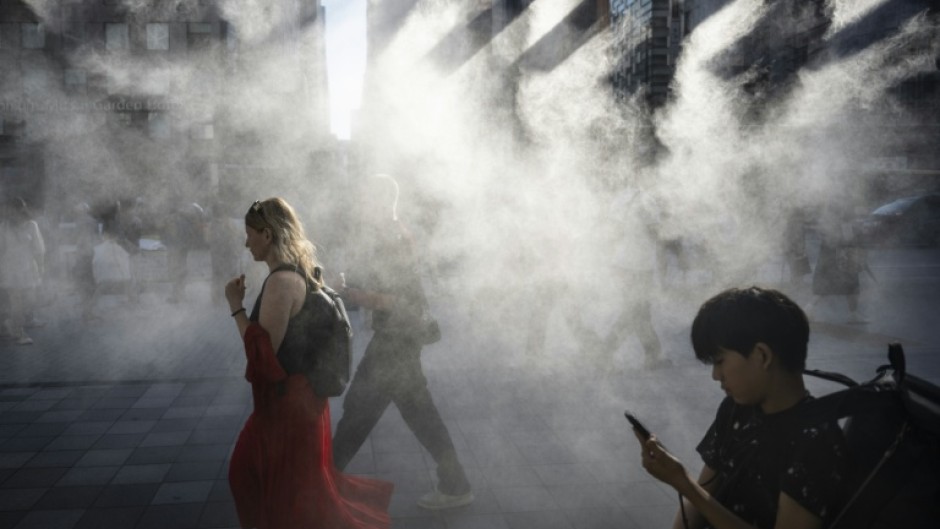 People walk under a misting system on a hot day in Tokyo earlier this year, which is on track to become one of the hottest in recorded history, according to the UN
