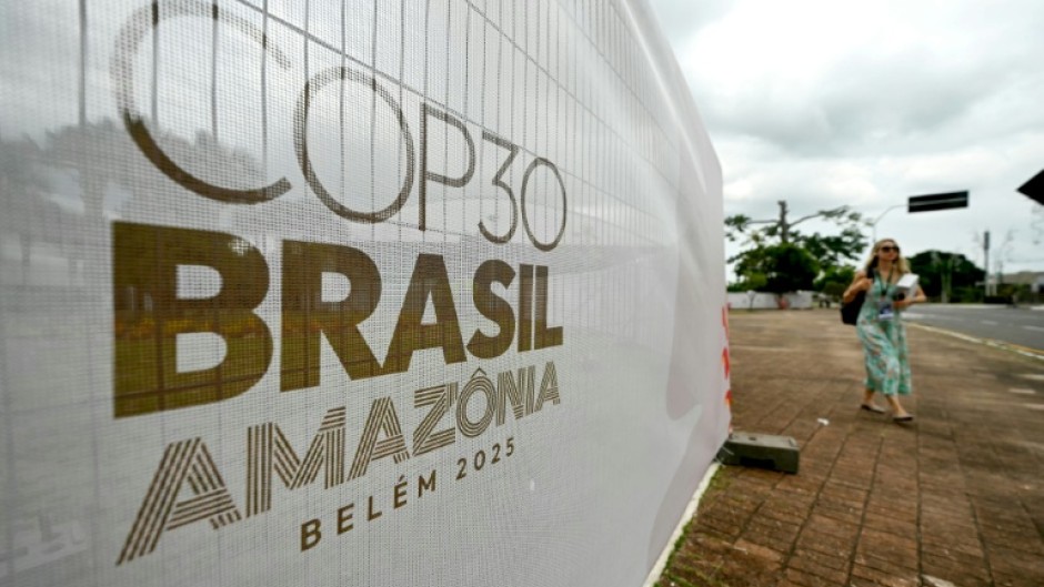 A woman walks past a banner with the COP30 UN Climate Change Conference logo outside the Hangar Convention and Exhibition Center in Belem, Para State, Brazil on November 5, 2025