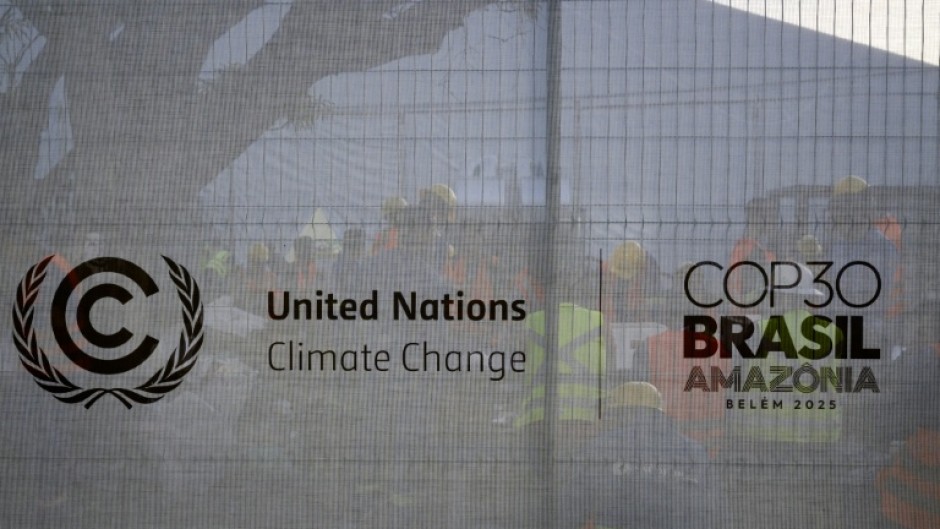 Workers rest behind a fence bearing the COP30 logo at a construction site in the City Park of the COP30, the United Nations Climate Change Conference in Belem, Para State, Brazil on November 3, 2025