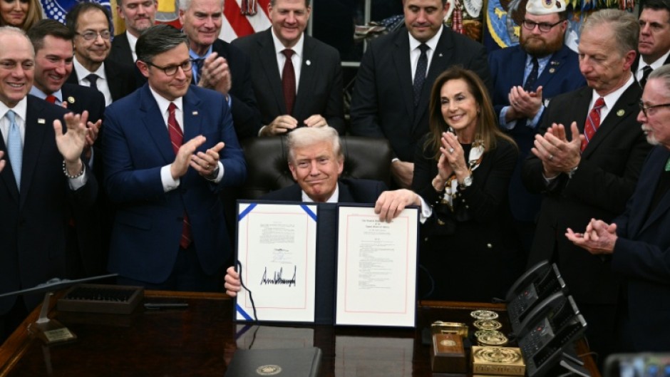 US President Donald Trump (C) shows the signed bill to re-open the federal government in the Oval Office of the White House