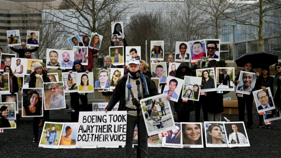 A man stands before photographs of victims of the Boeing 737 MAX crash in Ethiopia in March 2019, at a protest outside the US aircraft manufacturer's office in Arlington, Virginia