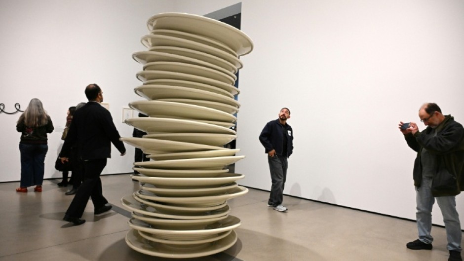 Visitors look at "No title (stacked plates, white)," a 1993 large-scale art work by Robert Therrien, during the exhibition "Robert Therrien: This is a Story" at The Broad in Los Angeles, California
