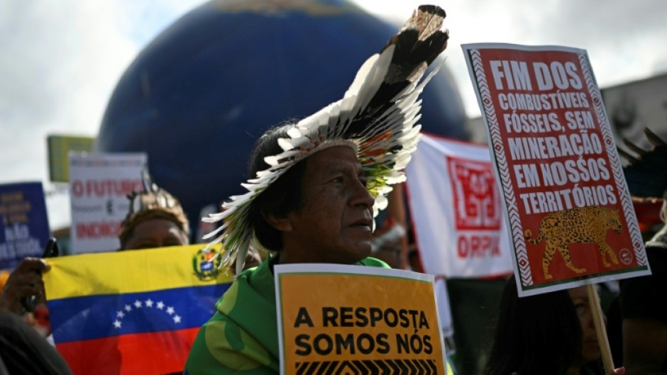 Indigenous people hold signs reading "The answer is us" and "End of fossil fuels, no mining in our territories" during a march on the sidelines of the COP30 UN Climate Change Conference in Belem, Brazil