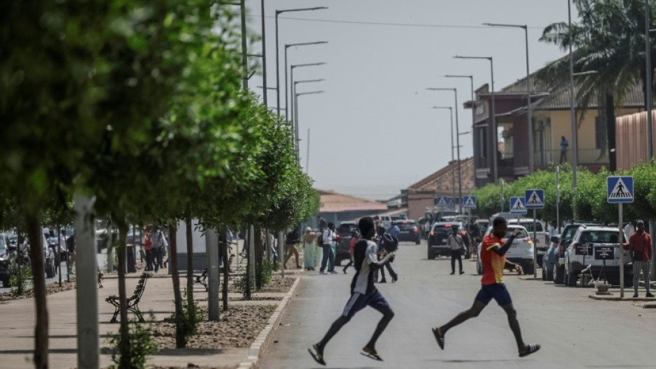 Men flee the scene as gunfire rings out near the presidential palace in Bissau on November 26, 2025