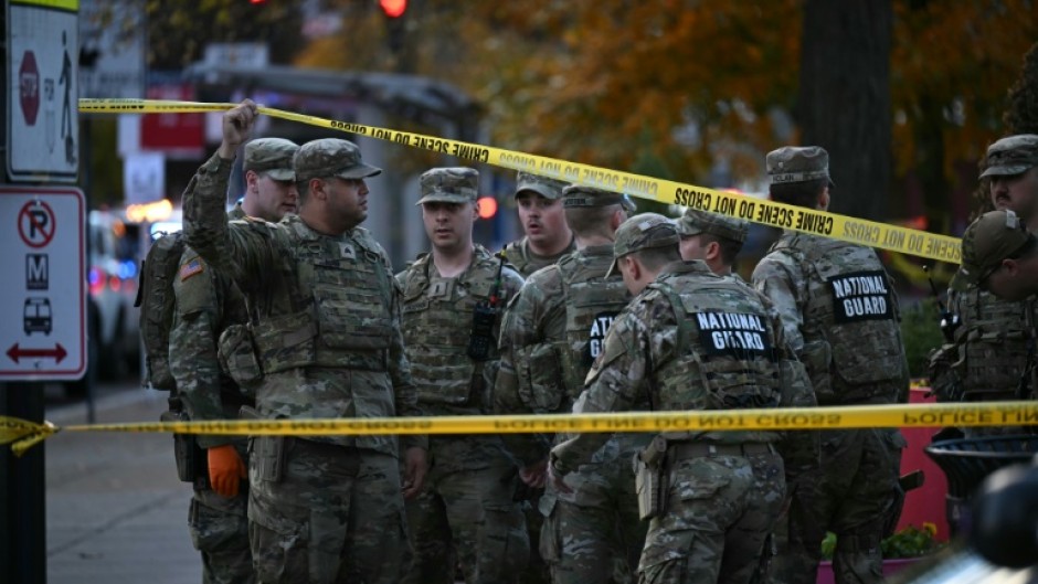 National Guard soldiers stand behind crime scene tape at a corner in downtown Washington where two National Guard soldiers were shot just blocks from the White House