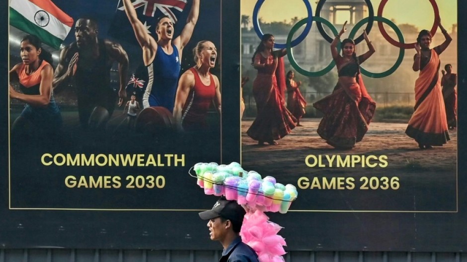 A cotton candy seller walks past a billboard in Ahmedabad