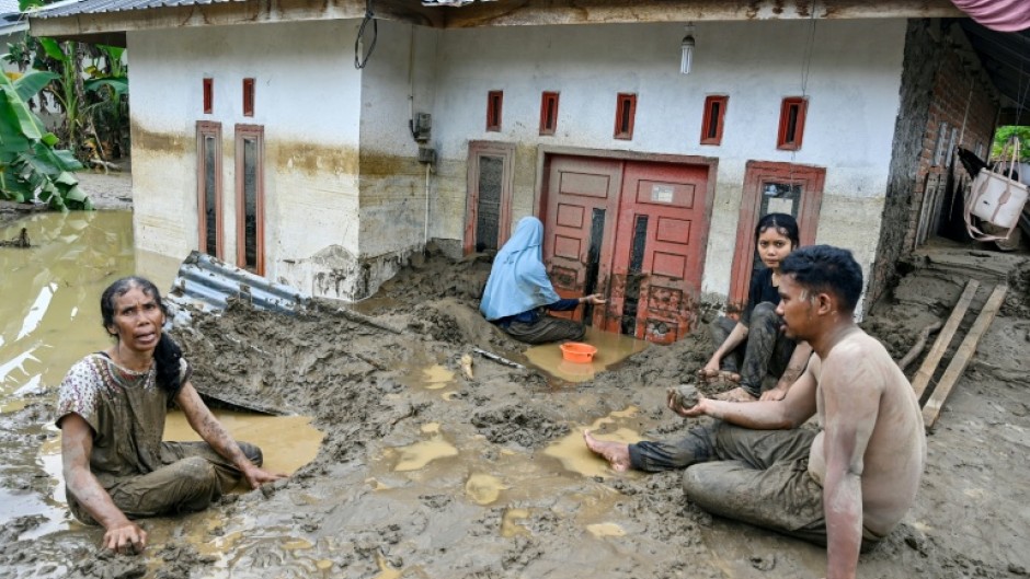 Dozens of people were killed in Indonesia's Aceh province, where residents cleared mud from flooded homes
