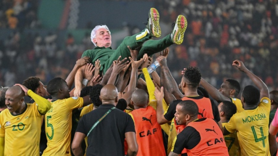 Coach Hugo Broos (C) is lifted as South Africa celebrate winning the 2024 Africa Cup of Nations third-place play-off against the Democratic Republic of Congo.