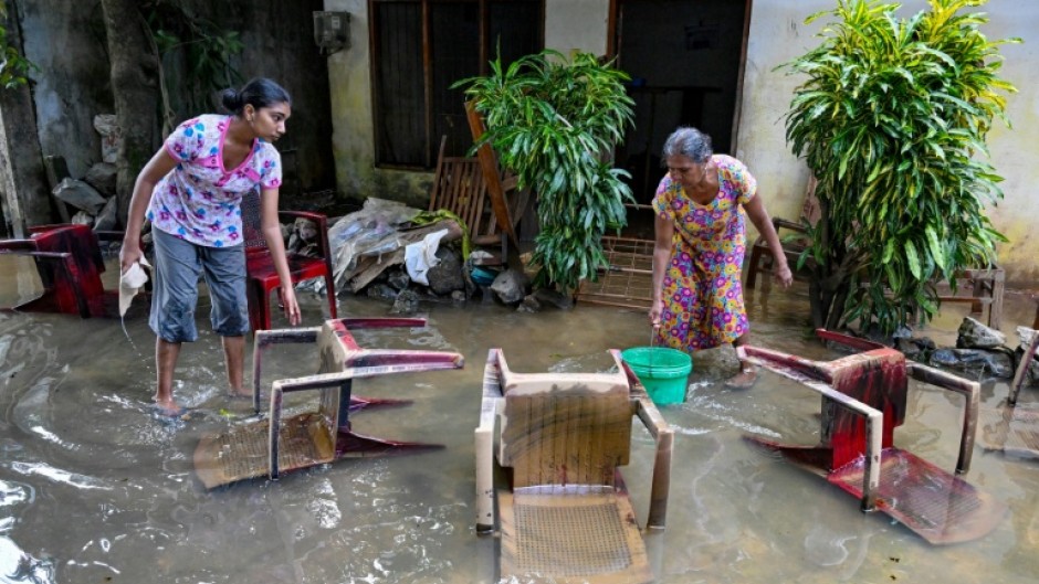 Residents salvage their belongings at an inundated house following flash floods in the aftermath of Cyclone Ditwah, in Wellampitiya on the outskirts of Colombo on December 3, 2025