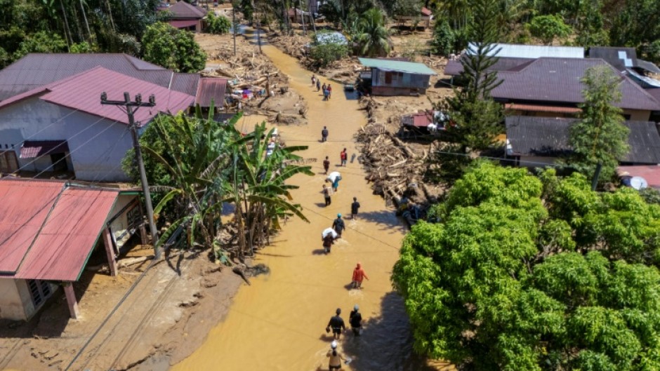 This picture shows an aerial view of villagers wading through the mudflow to find a shelter in the aftermath of flash floods in Tukka village, Central Tapanuli, North Sumatra province, on December 3, 2025