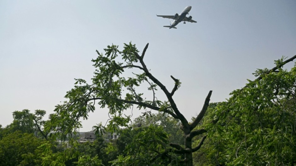 A commercial aircraft flies over the accident site of the Air India crash, still unresolved after six months