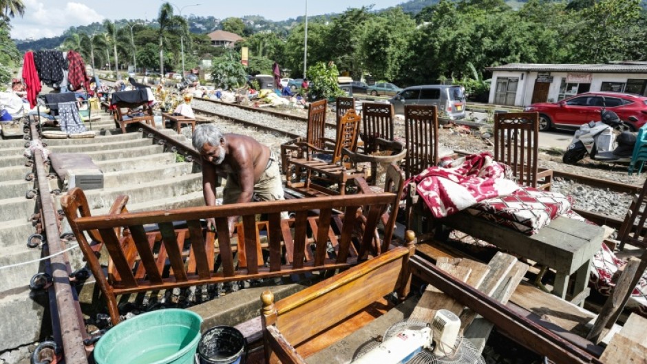 A Sri Lankan flood victim sorts out his belongings by railway tracks in Kandy. The authorities have issued fresh landslide warnings as monsoon storms make hillsides unstable