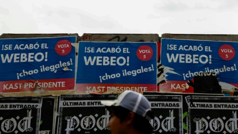 A person walks past posters supporting Chilean presidential candidate Jose Antonio Kast of the Republican Party in Santiago
