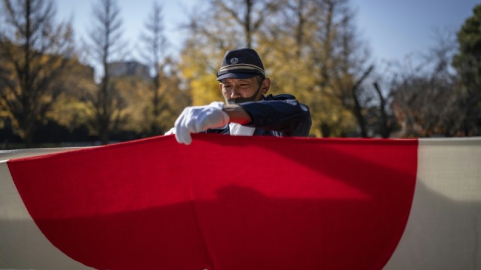 A member of the ultra-nationalist group Taikosha folds a Japanese national flag following a ceremony at Yasukuni shrine on the 84th anniversary of Japan's Pearl Harbour attack