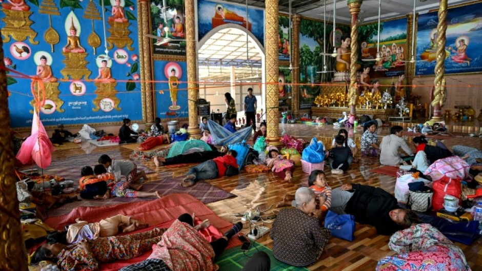 Residents rest inside a temple after they evacuated following clashes along the Cambodia-Thailand border, in Siem Reap province