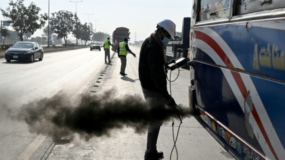 A technician examines a vehicle to test its emissions on road, at a checkpoint on the outskirts of Islamabad