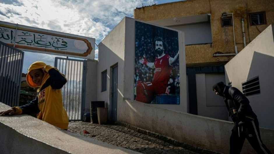 Locals pass a mural of Mohamed Salah at the entrance to the sports complex in his Egyptian home village of Nagrig